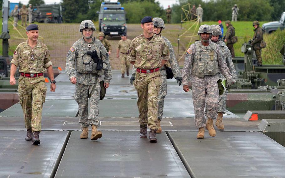 From left, British army Brigadier Robert Walton-Knight, commander of 8th Engineer Brigade; U.S. Army Lt. Col. Doug Lynch, commander of 5th Battalion; 7th Air Defense Artillery Regiment; British army Lt. Col. Alan Mason, commander of the 75 Engineer Regiment; and Sgt. Maj. George Clark of 5-7 ADA, cross an M3 Amphibious Rig bridge over the Wesel River in Germany. Patriot launcher stations later crossed the bridge during Minden Shock, a multinational training exercise, Tuesday, July 28, 2015.