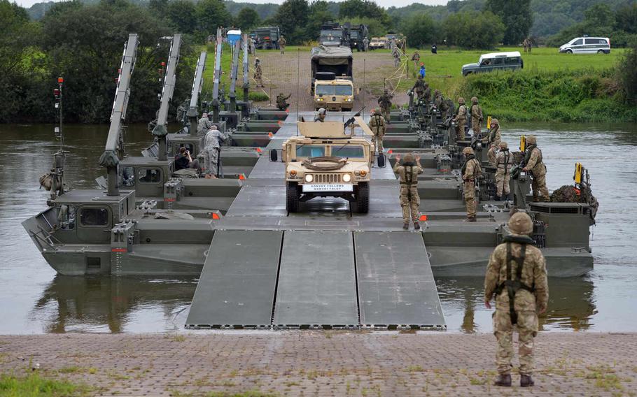 A convoy of U.S. Army vehicles cross the Weser River over a M3 Amphibious Rig bridge built by British and German army engineers during a training exercise in Germany dubbed Minden Shock. Soldiers of the 10th Army Air and Missile Defense Command's 5th Battalion, 7th Air Defense Artillery Regiment, drove a Patriot missile battery over the bridge before setting up the battery nearby, Tuesday, July 28, 2015.