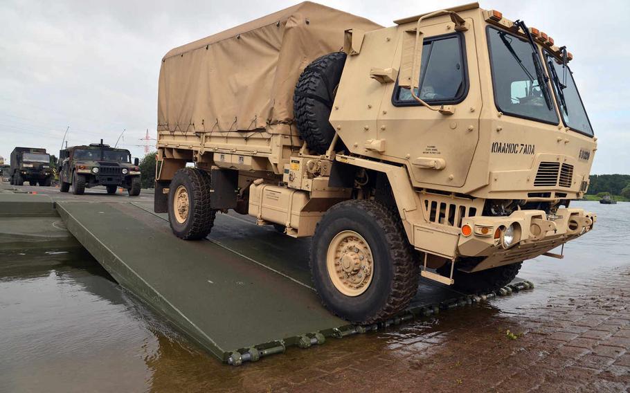 Vehicles of the the 10th Army Air and Missile Defense Command's 5th Battalion, 7th Air Defense Artillery Regiment, out of Baumholder, Germany, cross the Weser River over a temporary bridge built by British and German engineers near Petershagen, Germany, Tuesday, July 28, 2015.