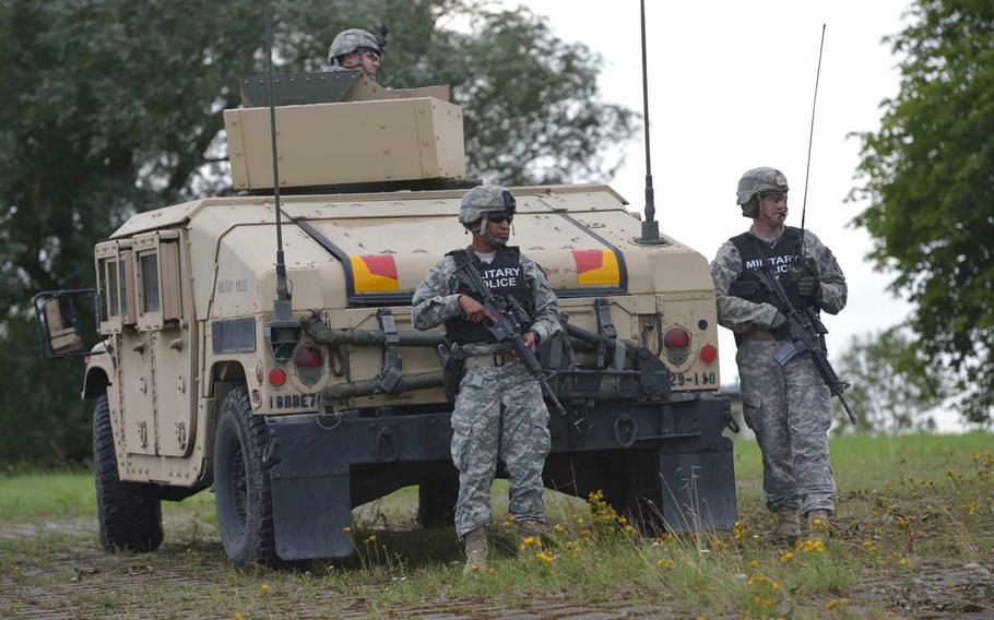 Soldiers of the 18th Military Police Brigade watch vehicles of the 5th Battalion, 7th Air Defense Artillery Regiment cross the Weser River near Petershagen, Germany, over a temporary bridge built by British and German army engineers, Tuesday, July 28, 2015.