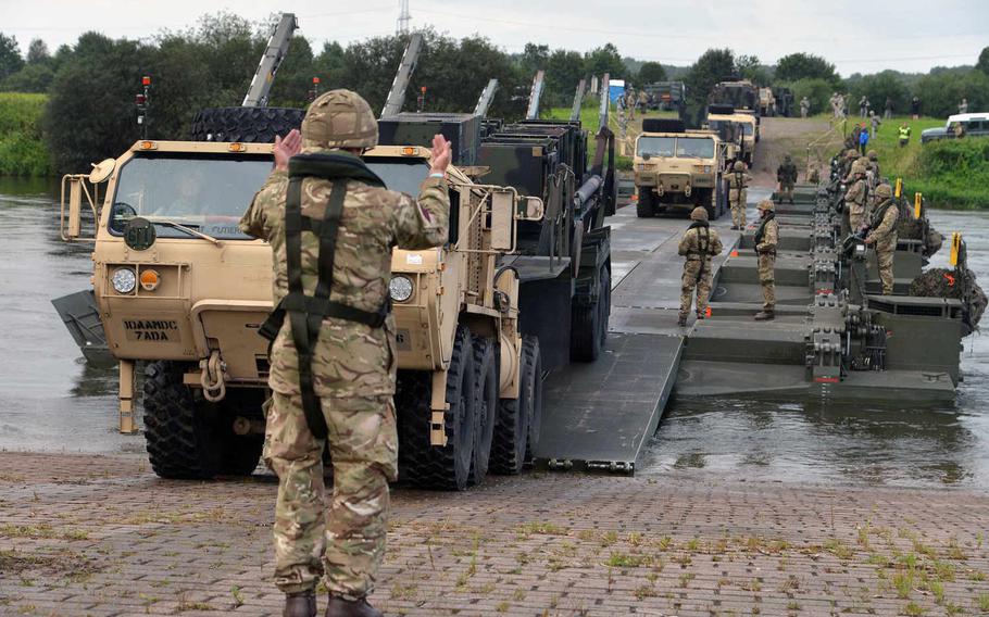 A British soldier guides a Patriot launcher station of 5th Battalion, 7th Air Defense Artillery Regiment, over an M3 Amphibious Rig bridge spanning the Weser River, Tuesday, July 28, 2015, during Minden Shock, a multinational training exercise.