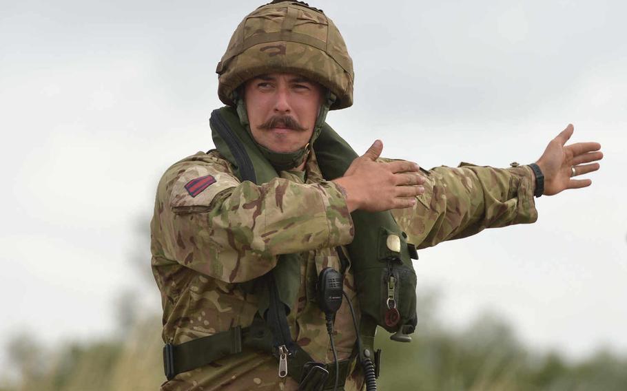 A British soldiers guides a U.S. Army vehicle over a temporary bridge spanning the Weser River, during Minden Shock, a multinational training exercise, Tuesday, July 28, 2015. British and German army engineers built the bridge using M3 Amphibious Rigs for the soldiers of 5th Battalion, 7th Air Defense Artillery Regiment, to cross.