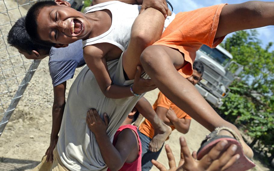 U.S. Air Force Senior Airman Charles Ballou, 823rd Expeditionary RED HORSE Squadron pavements and construction equipment operator, plays with local children near the well site in Brisas del Mar, Honduras, on Monday, Aug. 3, 2015.