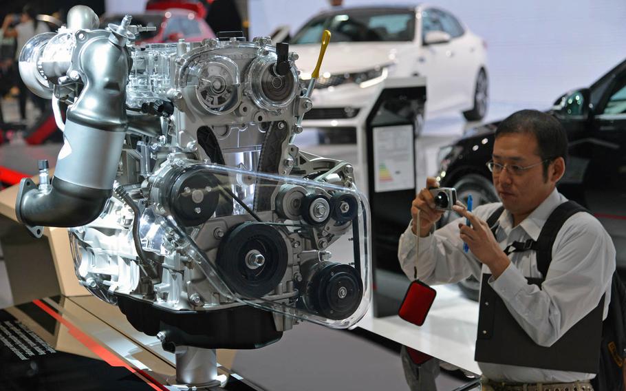 A visitor to the International Motor Show in Frankfurt, Germany, takes a photo of a 2-liter turbo Kia engine.