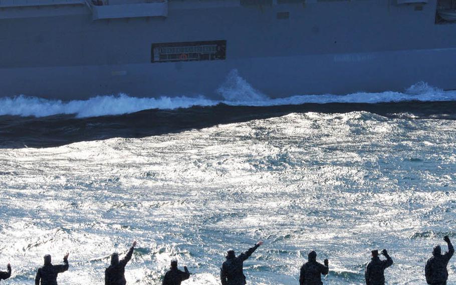 Sailors and Marines aboard the aircraft carrier USS Ronald Reagan wave to Japanese sailors aboard the Japan Maritime Self-Defense Force helicopter destroyer JDS Hyuga during a pass and review April 4, 2011. Ronald Reagan was operating off the coastline of Japan to provide disaster relief and humanitarian assistance in support of Operation Tomodachi.