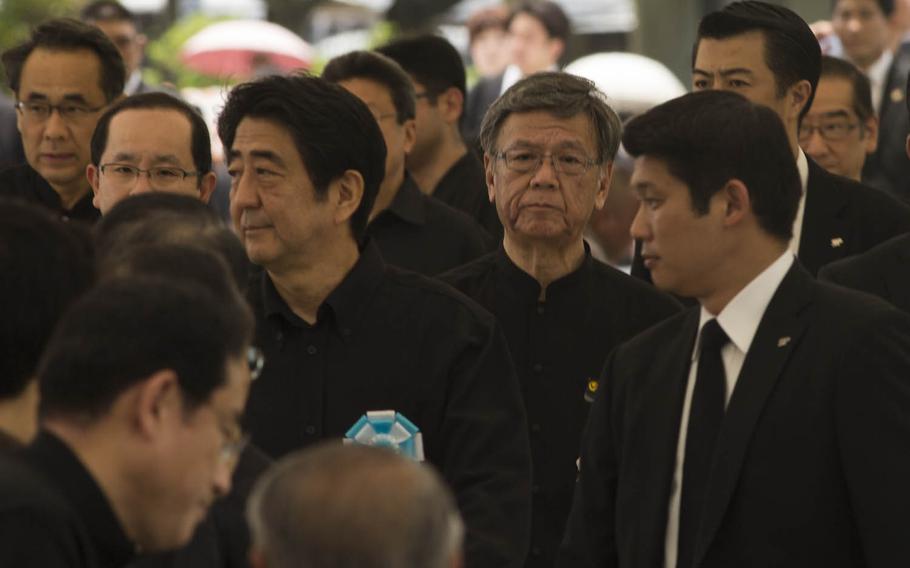 Prime Minister Shinzo Abe, center left, and Okinawa's Gov. Takeshi Onaga, center right, attend a memorial service honoring the fallen men and women of the Battle of Okinawa June 23, 2015, at Okinawa Peace Memorial Park. Onaga revoked a permit Tuesday, Oct. 13, 2015, for landfill work in Oura Bay for a U.S. military runway at Henoko, the latest salvo in his battle with Tokyo over American military posture on the tiny island prefecture.