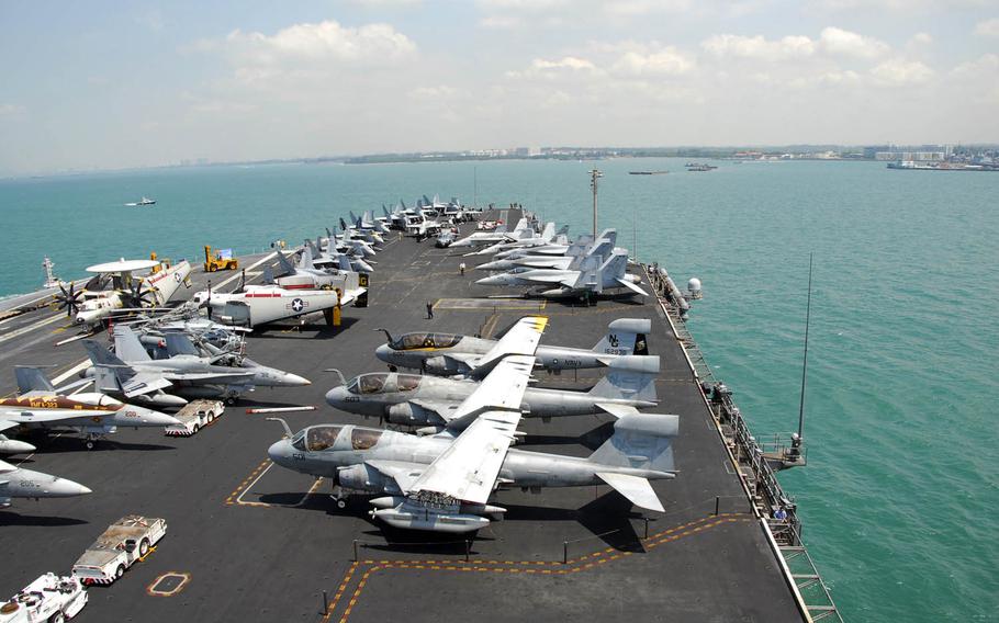 The aircraft carrier USS John C. Stennis transits Singapore harbor before mooring pier side at Changi Naval Base, Singapore, in 2009. A Singaporean woman is the latest former U.S. Navy official to be arrested in connection with a bribery scandal that traded classified ship information to a contractor in exchange for cash, travel and other perks.