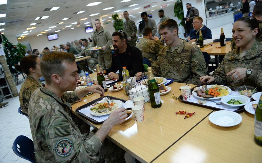 Navy Chief Tiffany Voels and Air Force Lt. Col. Ed Seibert, both foreground, eat Christmas dinner Friday, Dec. 25, 2015, at Resolute Support headquarters in Kabul, Afghanistan. 
                Heath Druzin/Stars and Stripes