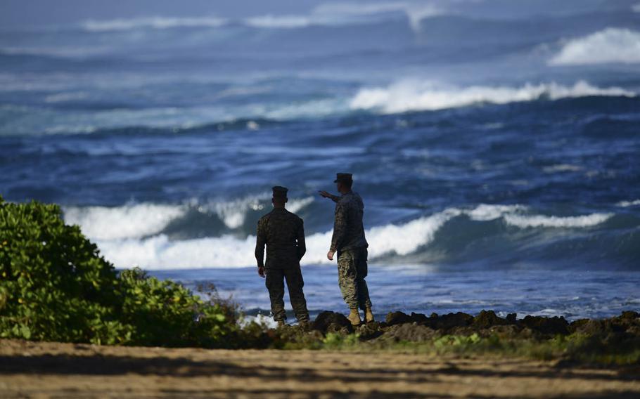 Marines discuss search efforts Monday, Jan. 18, 2016, in Haleiwa, Hawaii, after 12 Marines went missing following a helicopter crash off the North Shore of Oahu. The missing Marines are now presumed dead, and salvage operations are underway.