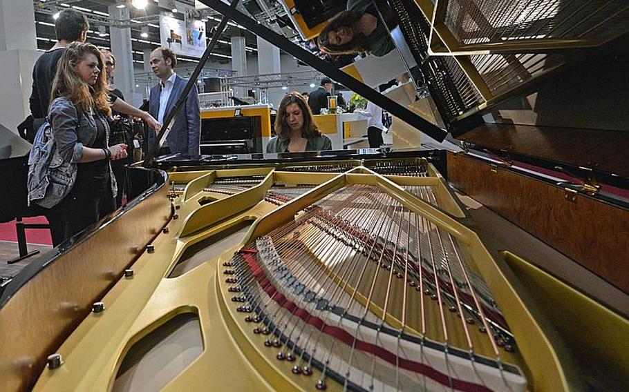 A visitor tries out a grand piano at the Grotrian-Steinweg stand at the Musikmesse in Frankfurt, Germany, Thursday, April 7, 2016. The music fair one of the world's largest, runs through April 10 at the Frankfurt fairgrounds.