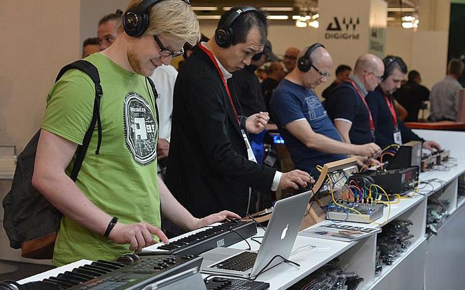 Visitors to the Musikmesse in Frakfurt, Germany, try out various electronic keyboards and synthesizers at the Korg stand, Thursday, April 7, 2016. The music fair is one of the world's largest.