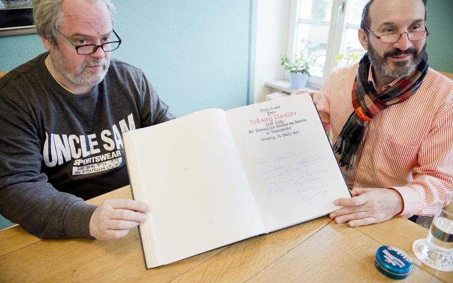 Guenther Jung, mayor of Baumholder, Germany, right, and Michael Roehrig, deputy mayor, display a guestbook signed by Hillary Clinton during her visit to the town hall as first lady in 1996.