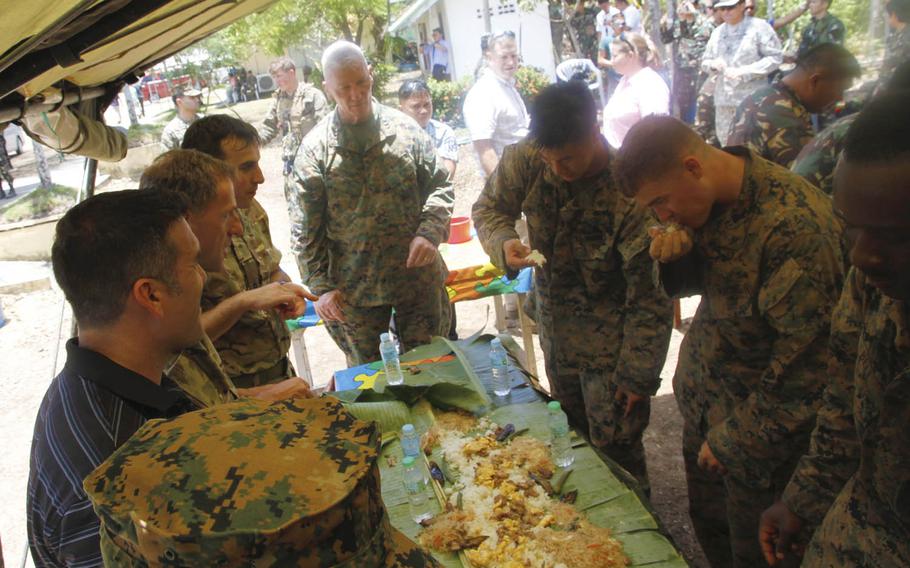 Marines join a traditional boodle meal with their Filipino counterparts Monday, April 11, 2016, near the airfield at Antique, Panay, Philippines, during Exercise Balikatan 2016. Diners stand shoulder-to-shoulder and eat the meats, rice and noodles with their hands.
