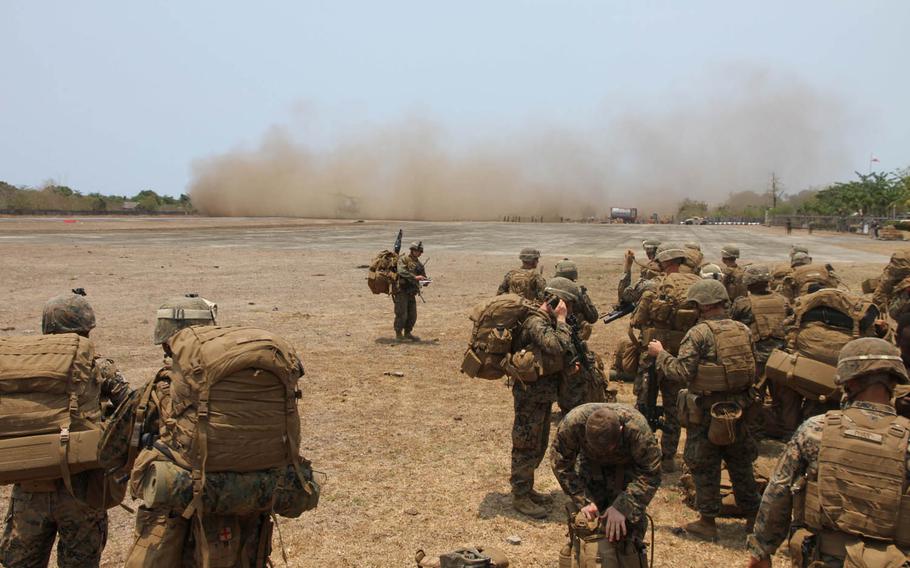 Marines from Golf Company, 2nd Battalion, 2nd Marines, watch as Super Stallion helicopters land at the airfield in Antique, Panay, Philippines, during Exercise Balikatan, Tuesday, April 12, 2016.