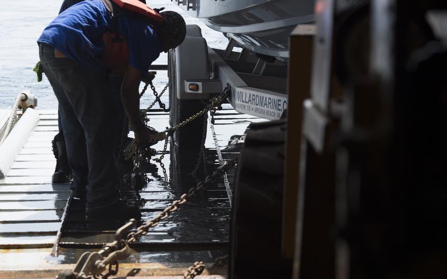 Personnel aboard the afloat forward staging base USS Ponce chain down a trailer holding a rigid-hulled inflatable boat during the International Mine Countermeasures Exercise April 10, 2016.