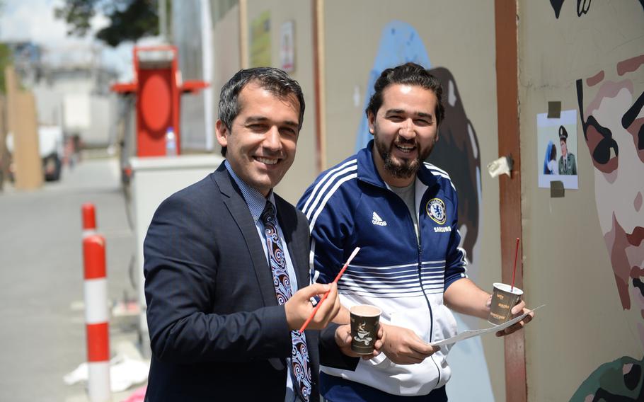 Sadiq Siddiqui, Afghan Interior Ministry spokesman, and Omaid Sharifi, a founder of Art Lords, participate in a Resolute Support mural paining on April 18, 2016.