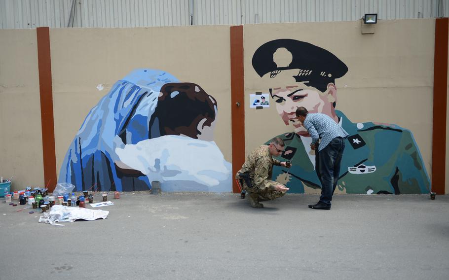 Army Lt. Col. Joe Reap and Noor Arzhang, an Art Lords member, paint a mural of a woman police officer at Resolute Support headquarters on April 18, 2016. Part of the project was aimed at fostering communication between servicemen and Afghan civilians.