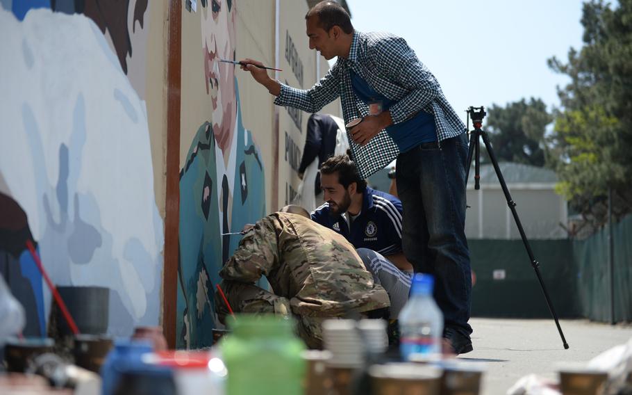 Members of the Art Lords group, which paints murals on Kabul's concrete blast walls, paint a mural at Resolute Support headquarters with servicemen on April 18, 2016.