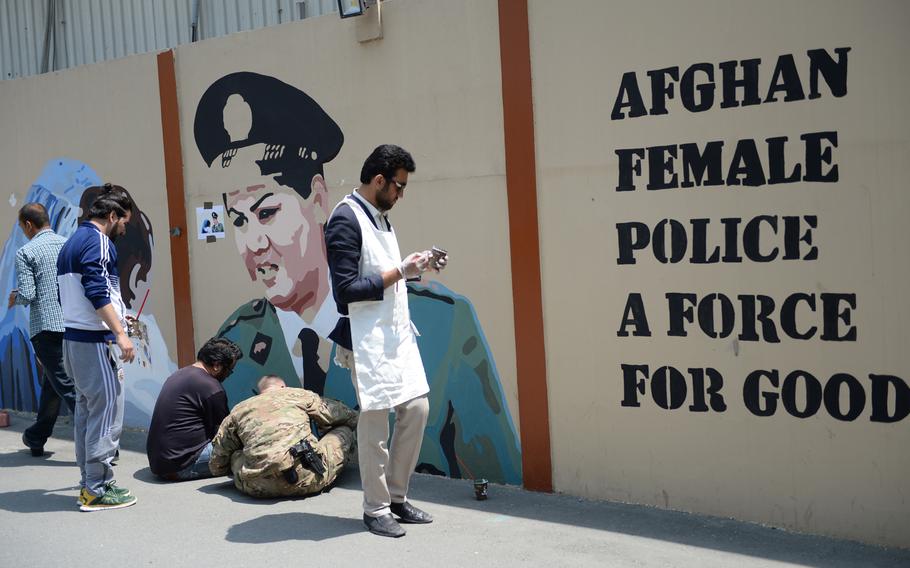 Members of the Art Lords group, which paints murals on Kabul's concrete blast walls, paint a mural at Resolute Support headquarters with servicemen on April 18, 2016.