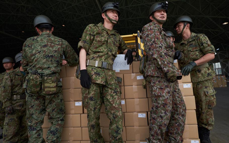 Soldiers from the Japan Ground Self-Defense Force wait to load a palette of food on to a U.S. MV-22 Osprey at Camp Takayubaru in Kumamoto, Japan, on Wednesday, April 20, 2016.