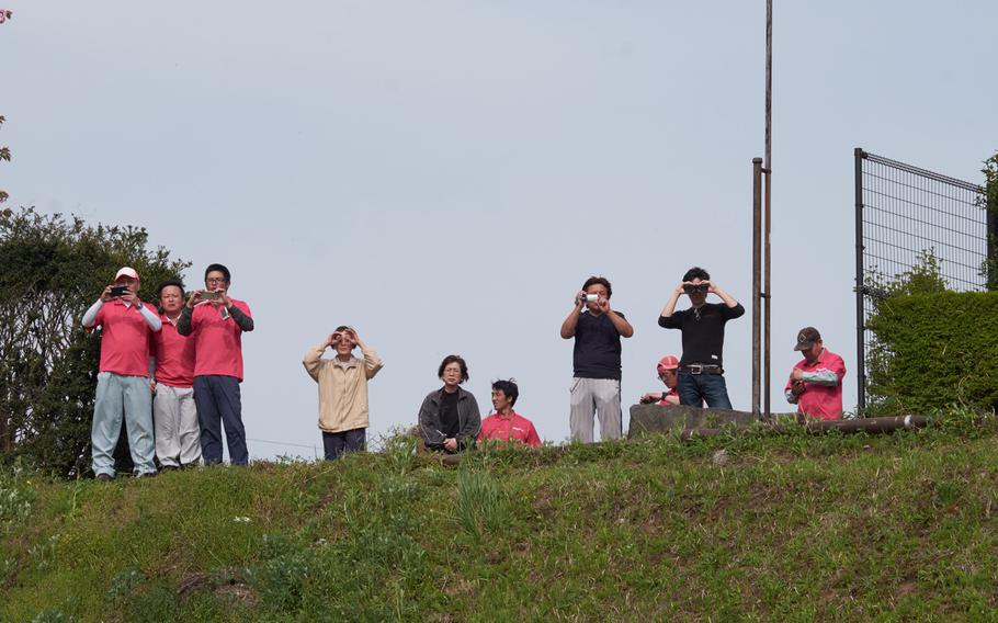 Residents living nearby Hakusui Sports Park watch and take photos of Japanese troops unloading a U.S. MV-22 Osprey in Kumamoto, Japan, on Wednesday, April 20, 2016.