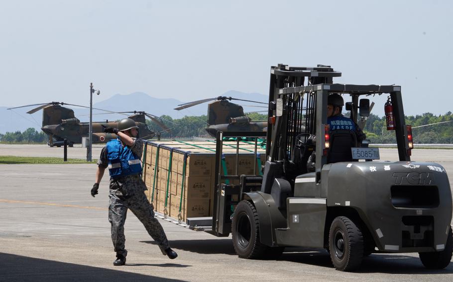 Airmen from the Japan Air Self-Defense Force haul cargo to a hangar bay at Camp Takayubaru in Kumamoto, Japan. The airmen are among the 20,000 Japanese troops deployed to Kumamoto to provide relief for earthquake victims.