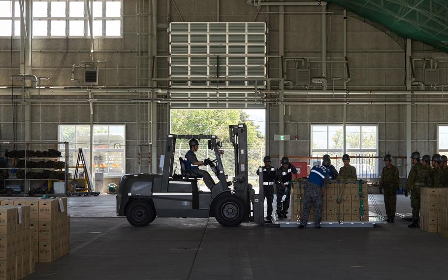 Airmen from the Japan Air Self-Defense Force and soldiers from the Japan Ground Self-Defense Force unload emergency aid at Camp Takayubaru in Kumamoto, Japan, on Wednesday, April 20, 2016. The camp is the main storage facility for emergency aid to be delivered to earthquake victims.