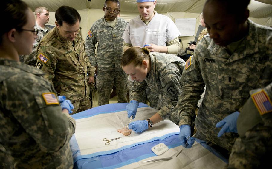 Col. William Stubbs, 30th Medical Brigade commander, left, watches 212th Combat Support Hospital nurses practicing sutures in Miesau, Germany, on Wednesday, April 20, 2016.