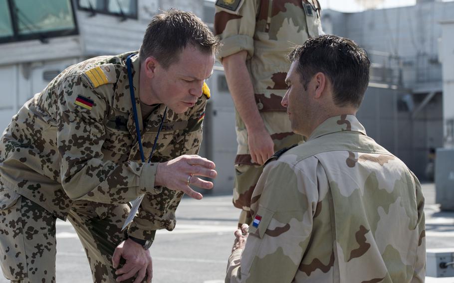 German navy Lt. Cmdr. Mario Fink, the on-scene commander for mine countermeasures operations around Kuwait during the International Mine Countermeasures Exercise, talks to a Dutch officer while the auxiliary expeditionary fast transport ship USNS Choctaw County leaves port in Bahrain on April 10, 2016.