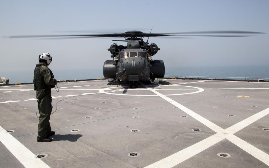 An aircrew member waits to board media on an MH-53E Sea Dragon, which is used by the U.S. Navy for airborne mine countermeasure missions, to transit them from the USNS Choctaw County during the International Mine Countermeasures Exercise on April 10, 2016.