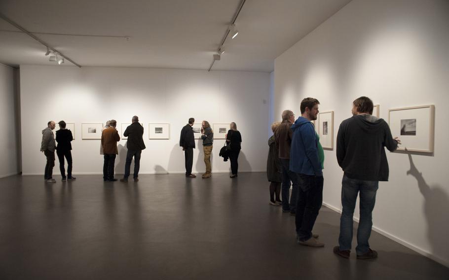 Visitors to the Pfalzgalerie in Kaiserslautern, Germany, discuss the photographs of Andre Kertesz during the opening of an exhibit devoted to the artist's work, April 15, 2016.