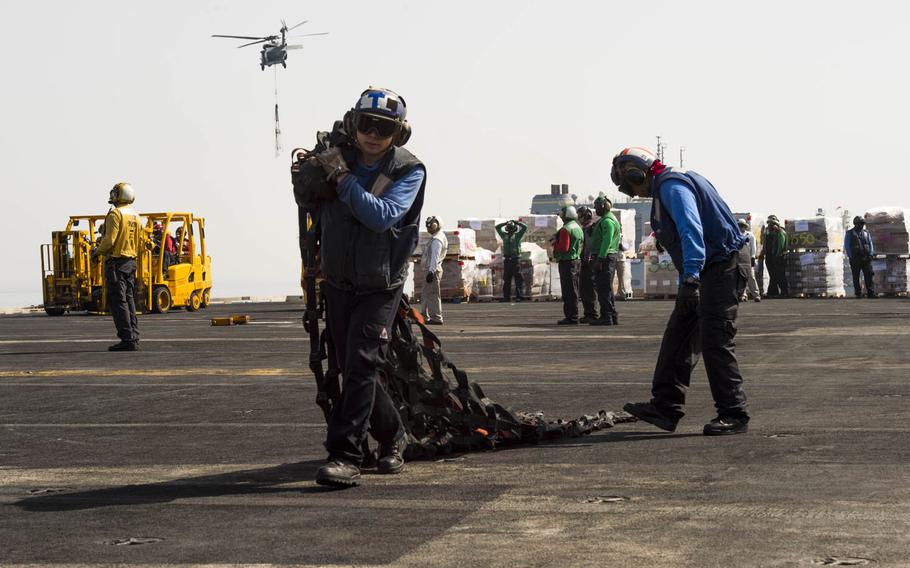 Airman Apprentice Skyler Vanoosten, an Aviation Boatswain's Mate Handling aboard the aircraft carrier USS Harry S. Truman, carries a net that was used to hold and transport a crate during a replenishment at sea across the flight deck on Tuesday, April 26, 2016.