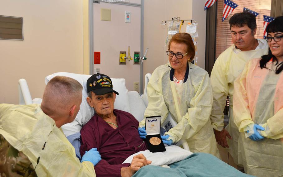 Army Col. Jeffrey Johnson, left, commander of Brooke Army Medical Center at Fort Sam Houston, Texas, presents the Congressional Gold Medal to retired Staff Sgt. Jose Diaz-Rivas last month for his service with the 65th Infantry Regiment during the Korean War, as his wife and family look on.