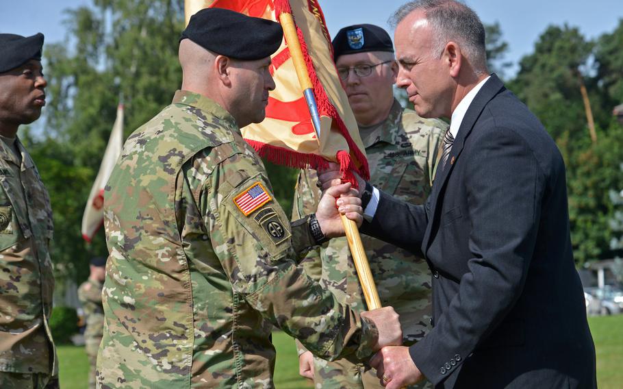 Outgoing U.S. Army Garrison Rheinland-Pfalz commander Col. G. Shawn Wells Jr. watches as incoming commander Col.Keith Igyarto takes the colors from Installation Management Command Europe regional director Michael Formica at the garrison's change-of-command ceremony in Kaiserslautern, Germany, Wednesday, July 6, 2016. At left is Command Sgt. Maj. Edward James Williams III.