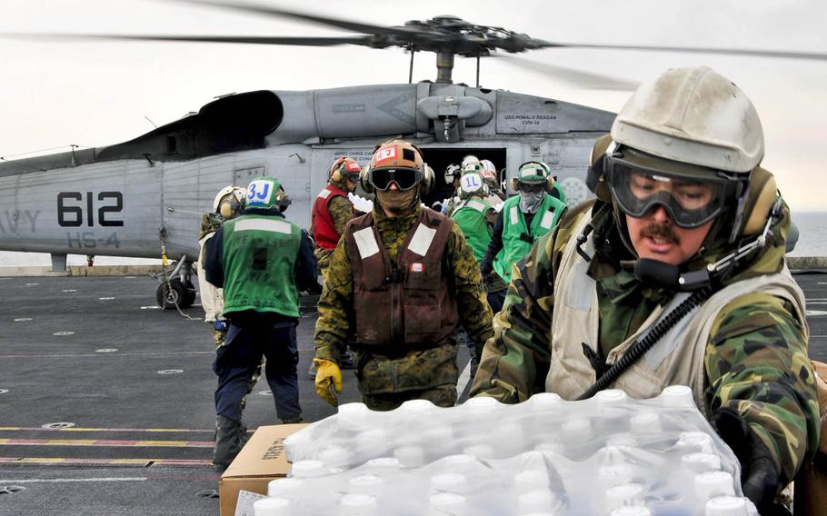 Sailors and Marines aboard the aircraft carrier USS Ronald Reagan load humanitarian supplies onto a Seahawk helicopter in the Pacific Ocean, March 19, 2011. The Ronald Reagan was operating off the coast of Japan in support of Operation Tomodachi.