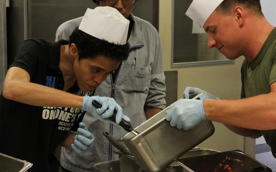Marine Lance Cpl. Jacob Tucker, right, helps a resident from the Reimei No Sato home for disabled adults apply toppings to his pizza on Thursday, July 7, 2016, at the 12th Marines Mess Hall on Camp Hansen. The ''Make your own pizza,'' event is one of hundreds of community relations events on Okinawa each year, and one of half a dozen between this particular home and 12th Marines.
