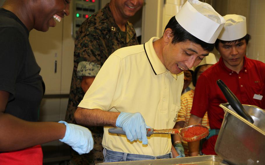 Marine Lance Cpl. Kyshia Holloway, left, helps a resident from the Reimei No Sato home for disabled adults sauce his pizza Thursday, July 7, 2016, at the 12th Marines Mess Hall on Camp Hansen as part of a ''Make your own pizza,'' community relations event. It was attended by about 30 adults from the home and about the same number of Marines and their families.