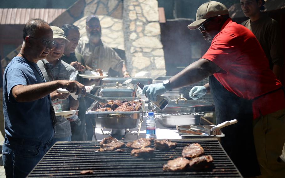 Dining facility supervisor Vince Drennen, right, prepares food for those attending Resolute Support's U.S. Independence Day celebration, belatedly held on Friday, July 8, 2016.