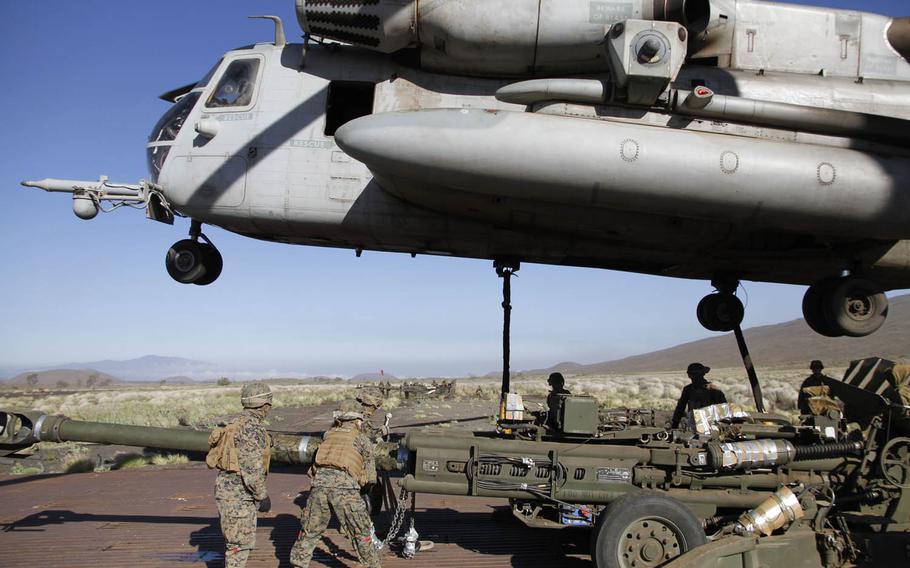 A Marine Corps Super Stallion helicopter hovers above a howitzer cannon as Marines below prepare it for a flight to the live-fire field at Pohakuloa Training Area on the big island of Hawaii, July 19, 2016.