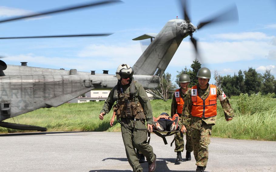 Marine Cpl. Kurt Bokern, left, a CH-53E Super Stallion crew chief from Marine Heavy Helicopter Squadron 361, jumps in and helps his counterparts from the Japan Ground Self-Defense Force as they carry a simulated casualty from the Super Stallion to a waiting ambulance during Japan's annual Churashima Rescue Exercise, Thursday, July 21, 2016. This year marks only the second time the Marines on Okinawa have participated and the first for HMH-361. The exercise is meant to prepare the allied militaries, emergency first responders and even local officials for a mega-disaster similar to the earthquake and tsunami that struck the Tohoku region in March 2011.