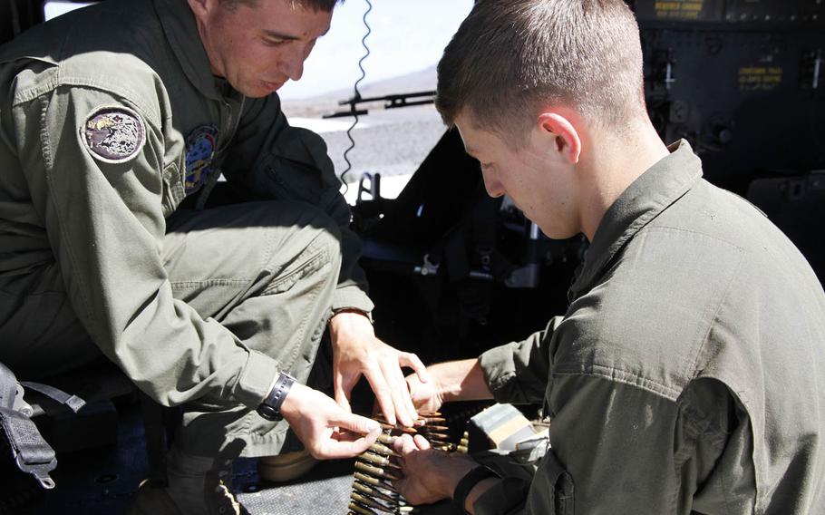 Staff Sgt. Benjamin Spitz, left, crew chief instructor aboard the Huey, shows a trainee crew chief how to prepare ammo for the helicopter's M240 machine gun at the Pohakuloa Training Area, Hawaii, July 20, 2016.
