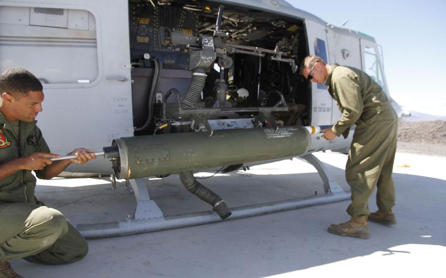 A 2.75-inch rocket is loaded and locked into place on a Huey helicopter's right rocket port by two Marines, July 21, 2016, at a forward arming and refueling point at Pohakuloa Training Area, Hawaii.