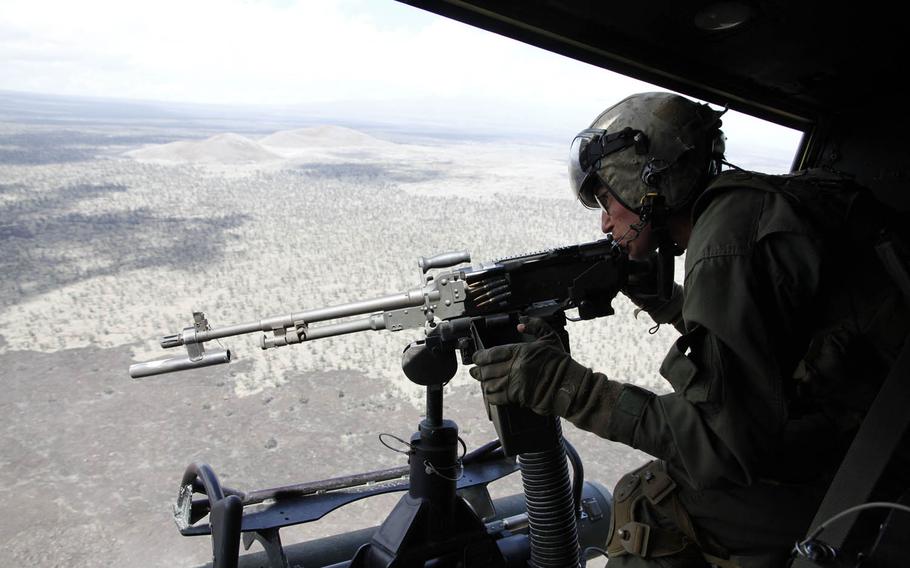 Staff Sgt. Benjamin Spitz, the crew chief instructor aboard the Huey, delivers short bursts of machine-gun fire at a target below on the live-fire range of the Pohakuloa Training Area, Hawaii, July 20, 2016.