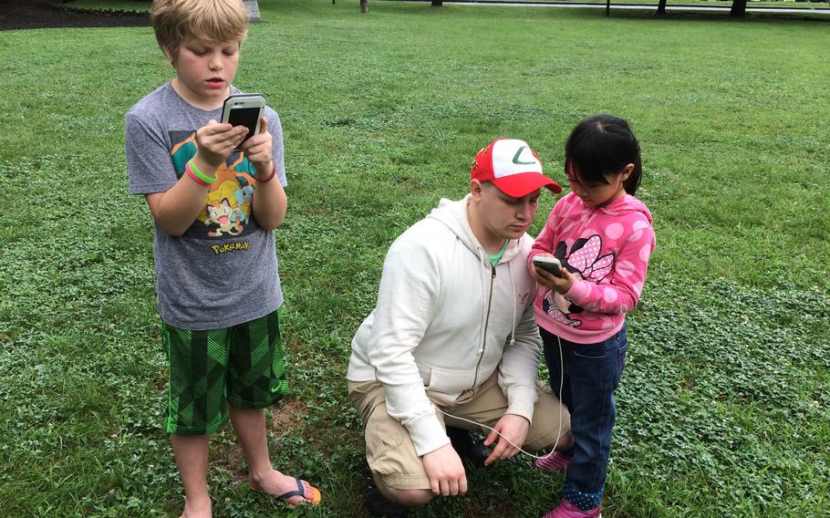 Air Force Staff Sgt. Richard Mahoney, 29, of Geneva, N.Y., hunts for Pokemon with his daughter, Julian, 6, at Yokota Air Base, Japan, Friday, July 22, 2016. The pair congregated with others at a "Pokestop" near the Sakura Shell outdoor stage in Yokota's east side housing area shortly after Pokemon Go went live in Japan.