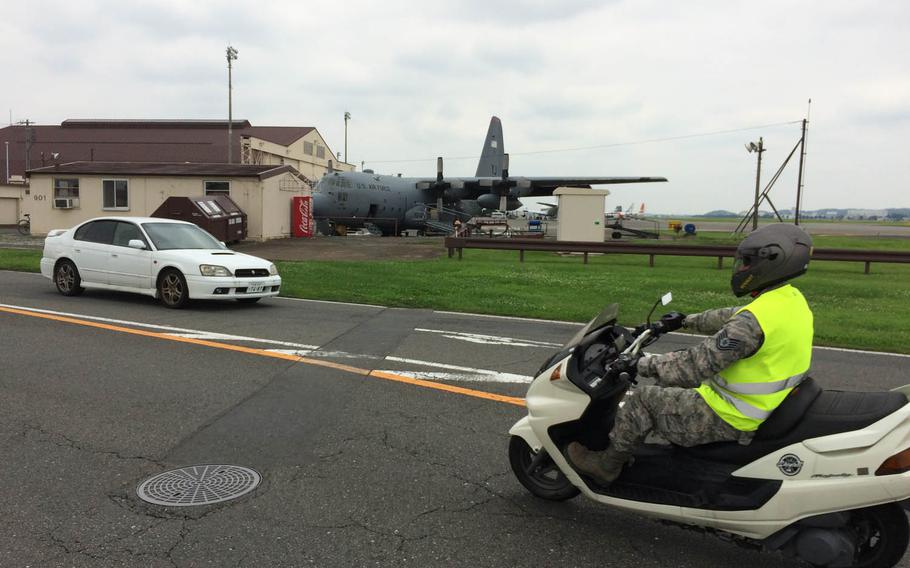 Motorists pass a C-130 Hercules near the flight-line at Yokota Air Base, Japan, July 25, 2016.