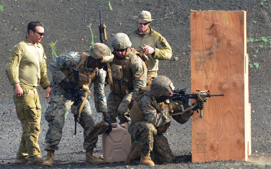 Marines compete in a timed marksmanship competition at Pohakuloa Training Area, Hawaii, during RIMPAC 2016, as two Australian soldiers monitor the event.