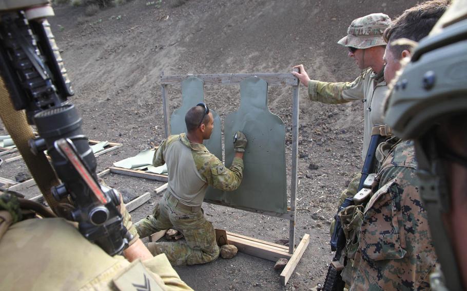 An Australian soldier monitoring a rifle competition between American and Australian troops marks hits and misses on targets as the participants watch at Pohakuloa Training Area, Hawaii, during RIMPAC 2016.