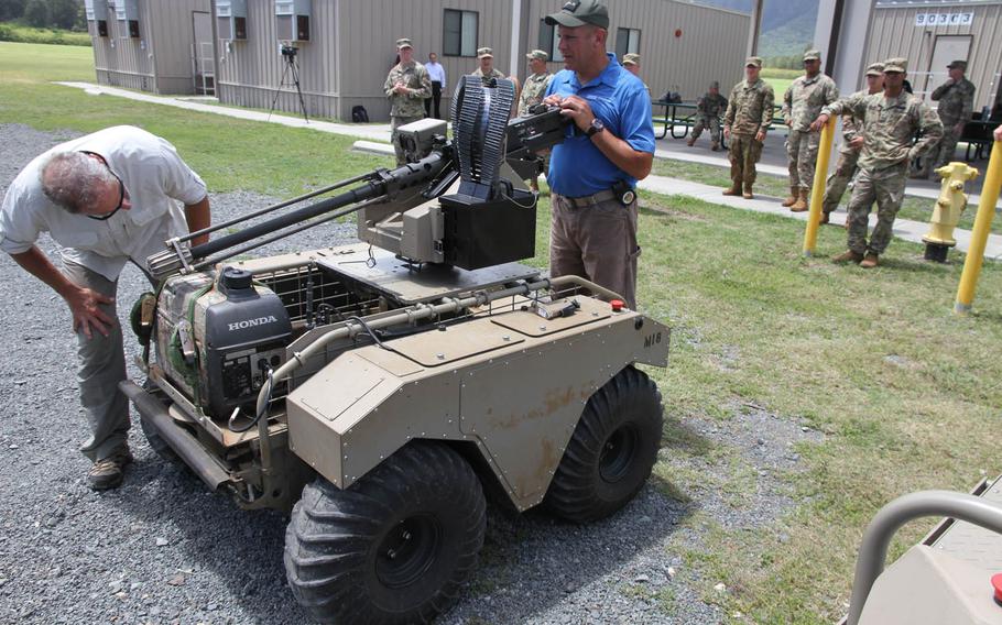 Technicians look over the Army's 600-pound Multi-Utility Tactical Transport, or MUTT, a prototype robot demonstrated at Bellows Air Force Station, Hawaii, July 26, 2016. Equipped with a remote-controlled M2 .50-caliber gun, the payload of the prototype can be swapped out depending upon the robot's mission.