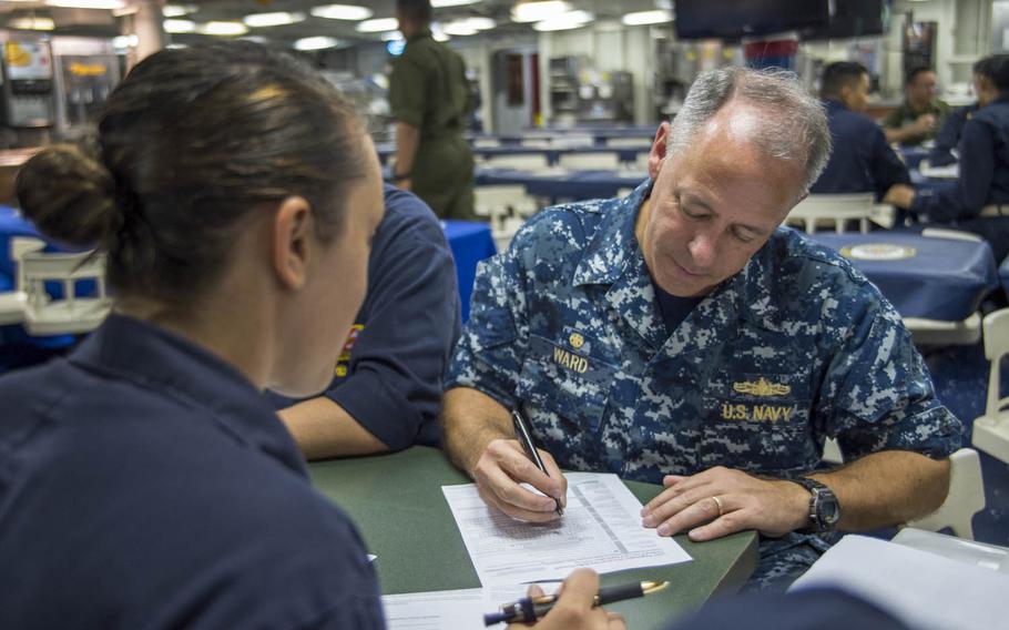 Capt. Jeffrey Ward, commander of the USS Bonhomme Richard, registers for an absentee ballot with help from Lt. j.g. Jessica Vaeth, the ship's voting assistance officer, while transiting the East China Sea, in August 2016.