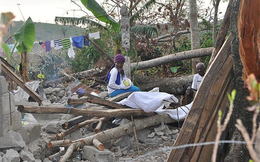 A woman holding a baby sits atop rubble in southwestern Haiti on Oct. 17, along the road between the southern coastal town of Les Cayes and the village of Jabouin in the nearby mountains. Hurricane Matthew smacked into the region two weeks ago, leaving an estimated 90 percent of the homes damaged or destroyed.